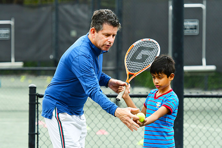 Coach David Freiman teaching young tennis student